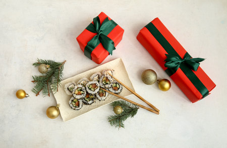 Plate of tasty sushi rolls with fir branches, gift boxes and Christmas balls on white backgroundの写真素材