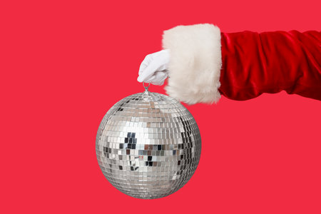 Santa hand with disco ball on red background, closeupの写真素材