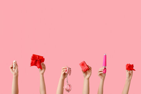 Female hands with sex toys and Christmas gifts on pink backgroundの写真素材