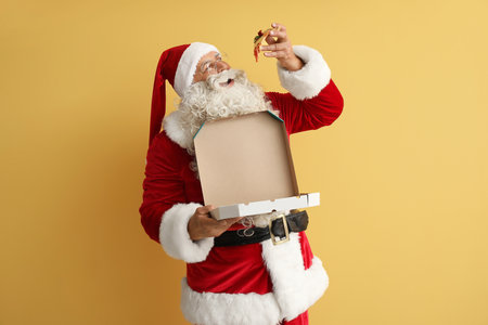 Santa Claus eating tasty pizza on yellow backgroundの写真素材