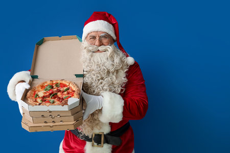 Santa Claus with boxes of tasty pizza on blue backgroundの写真素材