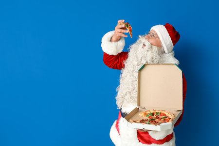 Santa Claus eating tasty pizza on blue backgroundの写真素材