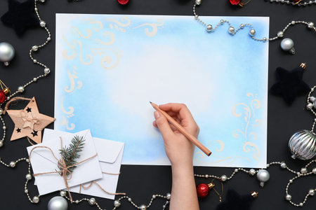 Female hand with Christmas card and decor on black backgroundの写真素材