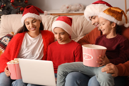 Happy family with popcorn watching Christmas movie on laptop at homeの写真素材