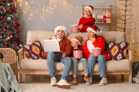 Happy family with popcorn watching Christmas movie on laptop at homeの写真素材