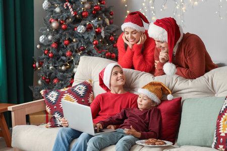 Happy family watching Christmas movie on laptop at homeの写真素材