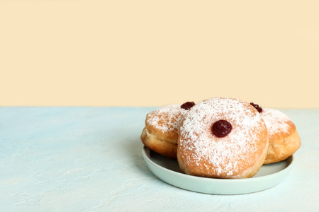 Plate with tasty donuts for Hanukkah celebration on color tableの写真素材