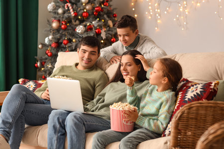 Happy family with popcorn watching Christmas movie on laptop at homeの写真素材