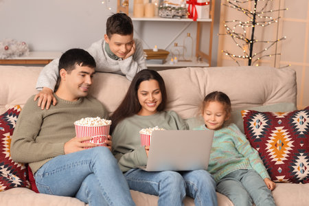 Happy family with popcorn watching Christmas movie on laptop at homeの写真素材