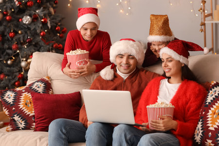 Happy family with popcorn watching Christmas movie on laptop at homeの写真素材