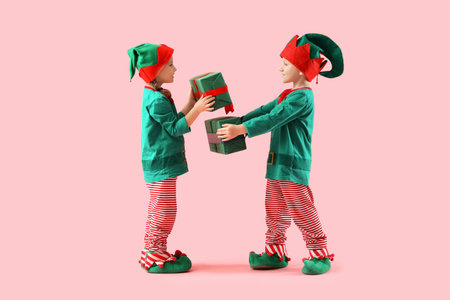 Cute little elves with Christmas gifts on pink backgroundの写真素材
