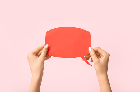 Female hands with blank speech bubble on pink backgroundの写真素材