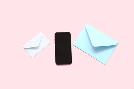 Mobile phone with blank screen and envelopes on pink backgroundの写真素材