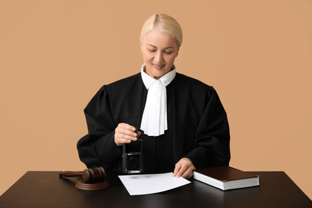 Mature female judge with stamp and document at table on brown background
