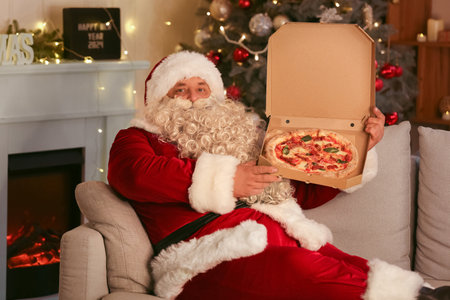 Santa Claus with tasty pizza lying at home on Christmas Eveの写真素材