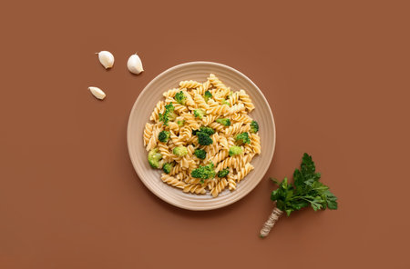 Plate of tasty pasta with broccoli on brown backgroundの写真素材