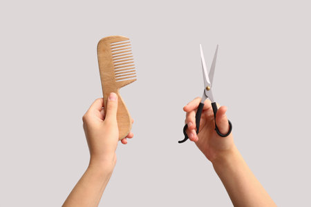 Female hands with comb and scissors on white background.の写真素材