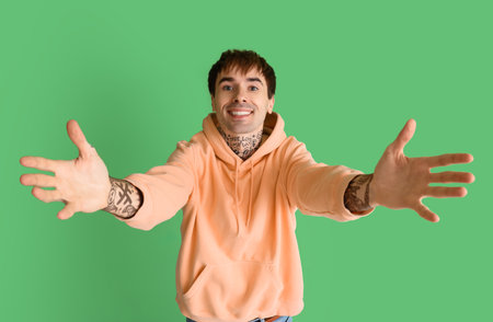 Young man opening arms for hug on green backgroundの写真素材