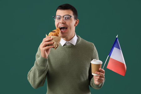 Young man with flag of France, croissant and coffee cup on green backgroundの写真素材