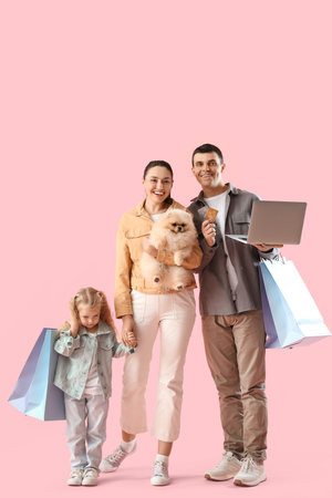 Happy family with laptop and shopping bags on pink backgroundの写真素材