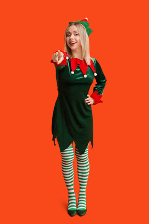 Young woman in elf costume pointing at something on orange backgroundの写真素材