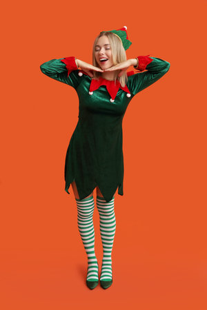 Young woman in elf costume on orange background