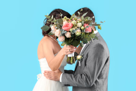 Young wedding couple with bouquet of flowers on blue background