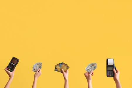 Female hands with credit card, payment terminals and money on yellow background