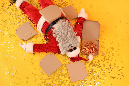 Cool Santa Claus with tasty pizza lying on yellow background, top viewの写真素材
