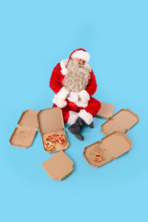 Santa Claus with tasty pizza on blue backgroundの写真素材