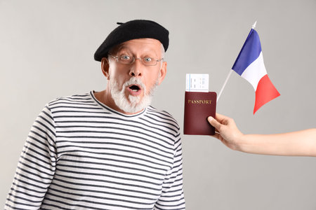 Shocked man senior and woman holding flag of France and passport on light backgroundの写真素材