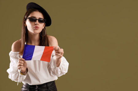Young woman with flag of France blowing kiss on green backgroundの写真素材