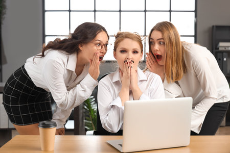 Female business colleagues gossiping in officeの写真素材