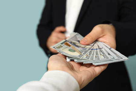 Young businessman giving bribe on blue background, closeupの写真素材