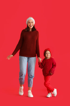 Happy young mother and her little daughter on red backgroundの写真素材