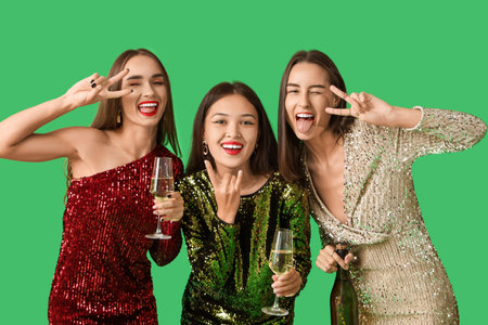 Beautiful young women with champagne on green background. New Year celebrationの写真素材