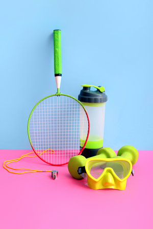 Badminton racket with dumbbells, swimming goggles and sports bottle on colorful backgroundの写真素材