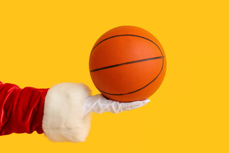 Santa Claus holding ball for playing basketball on yellow background, closeupの写真素材