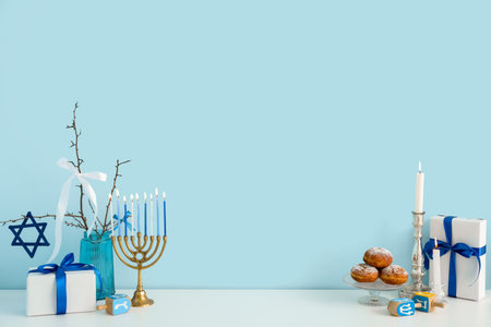 White cabinet with menorah, sufganiyots, dreidels and gift boxes near blue wall. Hanukkah celebrationの写真素材
