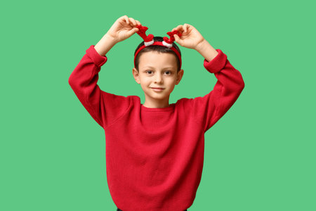 Cute little boy in reindeer horns on green backgroundの写真素材