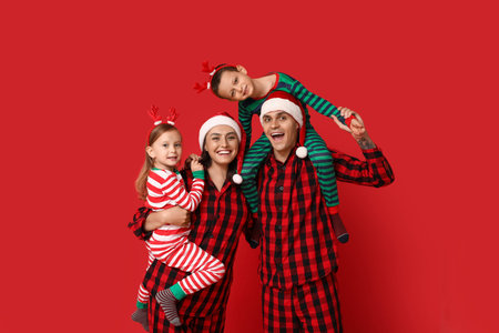 Happy family in Christmas pajamas on red backgroundの写真素材
