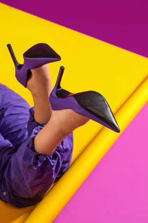 Woman in stylish high heeled shoes lying on color background, closeupの写真素材
