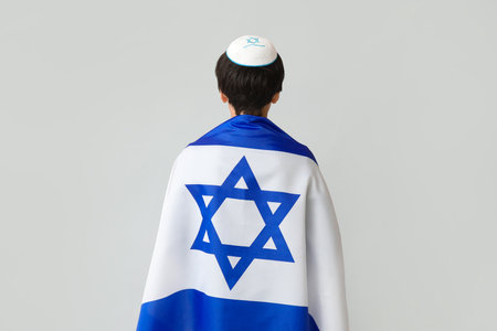 Little boy in kipa with Israel flag on gray background, back viewの写真素材