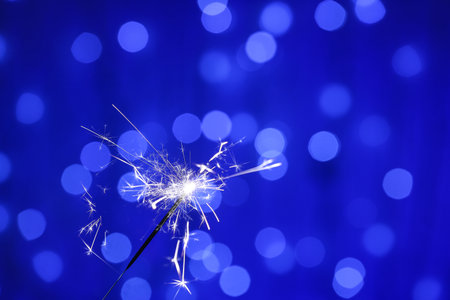 Beautiful Christmas sparkler on blurred lights backgroundの写真素材