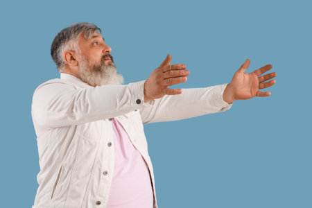 Mature man opening arms for hug on blue backgroundの写真素材