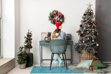 Woman working with laptop in office on Christmas Eve, back viewの写真素材