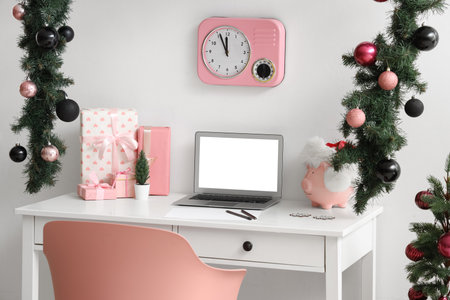 Workplace with blank laptop, presents and Christmas decor in officeの写真素材