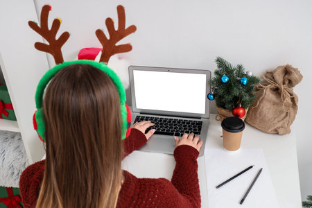 Woman working with laptop in office on Christmas Eve, back viewの写真素材