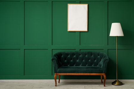 Modern green sofa with lamp and frame near green wallの写真素材