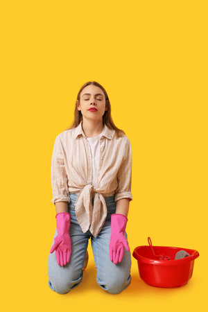 Beautiful young housewife with basin meditating on yellow background. Zen conceptの写真素材